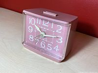 Front and angled view of the vintage pink Westclox electric alarm clock showing the clock face, pink plastic body, and top button.