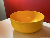 Side angle of the yellow plastic mixing bowl showing smooth rounded shape and thick rim.