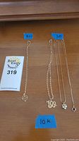 All four necklaces laid out on wooden surface with lot tag