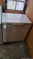 Closed view of beige Kenmore chest freezer from the side, showing overall shape and color.
