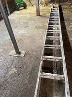 Full view of aluminum extension ladder laid out on floor showing rungs and general length.