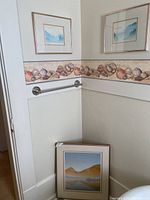 Two smaller framed prints hanging on walls and one larger print resting on floor, showing overall condition and framing.