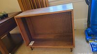 Front view of the mid-century modern mixed wood toned shelf, showing open storage space and pegboard back panel.