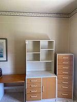 Overall view of the three furniture pieces: small desk, bookshelf, and 8-drawer cabinet in a room corner