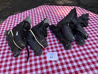 Two pairs of black kids rollerblades on red and white checkered cloth