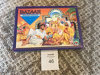 Closed Bazaar Special Edition game box on carpet, showing cover art of Middle Eastern market scene with people relaxing and playing.