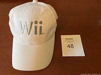 Front view showing white baseball hat with silver Wii logo and MaxSold lot number card
