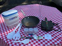 Overall view of small kitchen items including wok, sandwich maker, storage containers, utensils, and bottles.