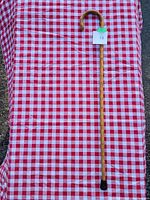 Full view of the 33.5 inch wooden walking stick with curved handle placed on red and white checkered cloth.