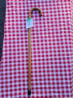 Full length view of the wooden walking stick laid on a red and white checkered cloth.