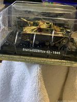 Front and side view of the Amercom German Sturmtiger tank 42-1945 1/72 scale model in clear plastic display case with black base showing camouflage paint and military markings.