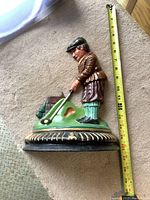 Side and front view of the detailed painted cast iron male golfer door stop with measuring tape showing about 12 inches height.