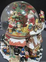 Wide view of snow globe showing Santa, children inside the dome, reindeer on roof, and base scene with people and snowmen