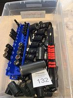 Plastic container filled with black sockets and blue socket holder with numbered slots 6 to 15, plus a black rail with red clips.