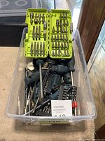 Plastic container filled with assorted screwdrivers and green case with screwdriver bits