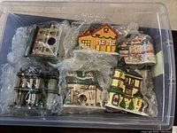 Plastic container with six ceramic Christmas village buildings wrapped in bubble wrap