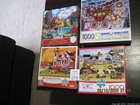 Four 1000-piece puzzles shown stacked on a sofa including mountain cabin, Western stagecoach, town scene, and Charles Wysocki puzzle.