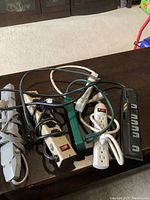 Lot of six power bars on a wooden table with visible multiple outlets and power switches