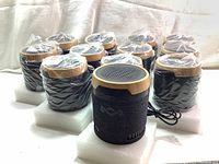 Photo of 12 House of Marley Chant Mini speakers individually wrapped in plastic on styrofoam trays, showing uniform packaging and condition.