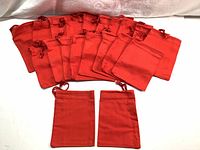 Top view showing multiple red fabric drawstring pouches arranged in a row with two additional pouches laid flat.