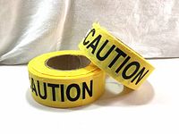Two rolls of bright yellow fabric caution tape with black 'CAUTION' lettering, positioned on a white backdrop.