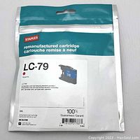 Photo of the sealed pouch containing the remanufactured Brother LC79 magenta ink cartridge by Staples, showing label with part number, color, and compatible printer models.