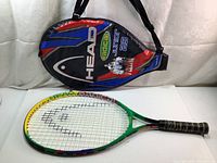 Photo showing the Head Radical Junior 23 tennis racquet alongside its protective cover, which has a strap and colorful branding.
