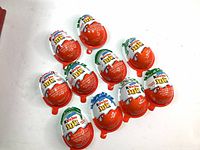 Ten Kinder Joy eggs arranged on a white surface showing brand colors and design without any opened toys.