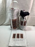 Two canvas wine gift bags displayed standing upright; one with handle and one with drawstring top, both white with printed phrase and wine cork illustrations