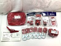 Big lot contents arranged including Brady red bag pouch, ball valve lockout device, padlock hasps, and lockout accessory bags.