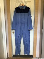Front view of new blue heavy duty coveralls jumpsuit with darker blue shoulder area, multiple pockets, long sleeves, collar and zipper.