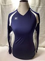 Front view of Mizuno dark blue and white long sleeve athletic shirt on mannequin, showing fitted profile, V-neck collar, and Mizuno logo on chest.