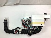 Full view of the complete dispenser assembly showing white control housing, flexible black tubing with connectors, and wiring harness with electronic components.