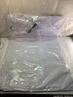Front view of the packed Sammons Preston bed sensor pad showing the pad and attached cable inside clear plastic wrapping.
