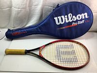 Full view of Wilson Stixx 23 tennis racquet laid flat with Wilson Pro Staff blue carrying case in background.