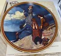 Plate 'Waiting On The Shore' with detailed Norman Rockwell scene of four women on a sand dune looking at the sea, showing gold rim and part of original box underneath