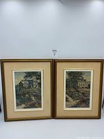 Two framed prints hanging side-by-side, showing mill and garden scenes with visible water stains and discoloration.