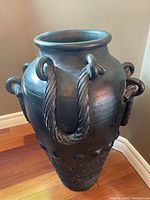 Full view of large black pottery floor vase showing shape and handles