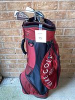 Red and black Nike Golf bag with white logo embroidered on side pocket. Shows some wear signs.