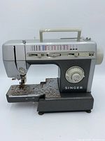 Side view of Singer CG-590C sewing machine showing overall shape, color, handle, controls and rust on base plate