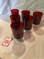 Set of six red glass wine glasses arranged in two rows on a white background - to show the quantity and overall form.