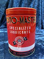 Front view of red Moto-Master oil tin piggy bank with branding and logos.