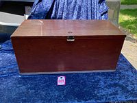 Front exterior of vintage wooden mechanic's box with metal trim on dark fabric background with lot number.