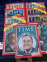 Full top-down image showing nine vintage TIME magazines stacked and spread out, with visible headlines and images.