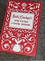 Front cover of the 1950s Betty Crocker's Picture Cook Book showing the red cover with white floral designs and title.
