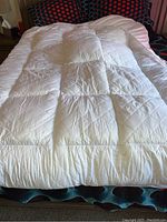 Top view of white quilted queen size cushion top mattress pad laid on bed.