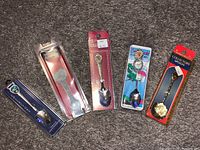 Full view of five collectors spoons in original packaging laid out on carpet