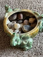 Top-down view of green elephant glass dish filled with assorted polished stones