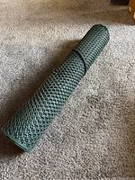 Side view of the rolled green plastic fencing with hexagonal mesh pattern.
