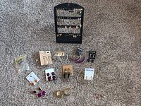 Full view of assorted earrings including studs, hoops, and danglers displayed on black earring holder and carpeted surface.